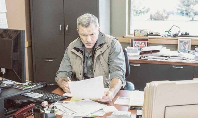 Business owner sitting at a desk reading a document.