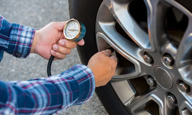Employee checking tire pressure as part of their daily fleet management checklist.
