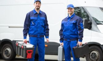Two plumbers outside their fleet van.