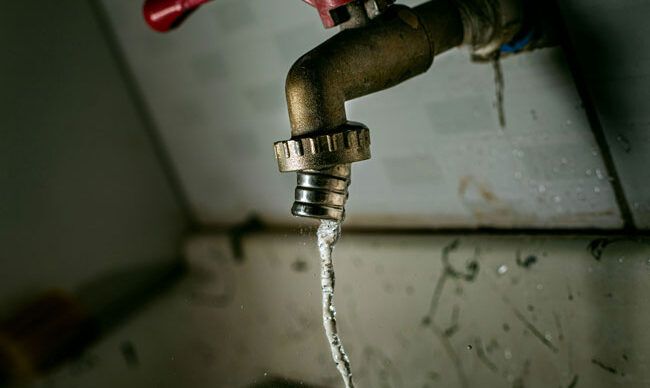 A faucet is on with water dripping down.