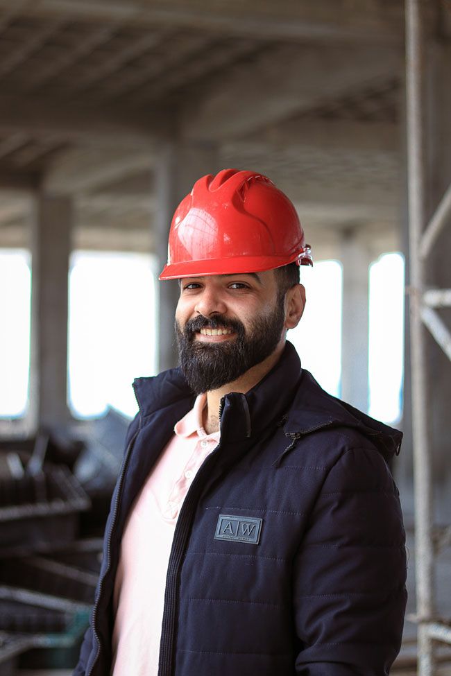 A happy construction owner of a fleet of vehicles wearing a hardhat.