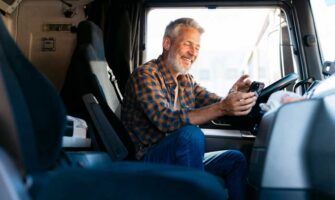A happy truck driver uses his fleet fuel card app to load information about his rig.