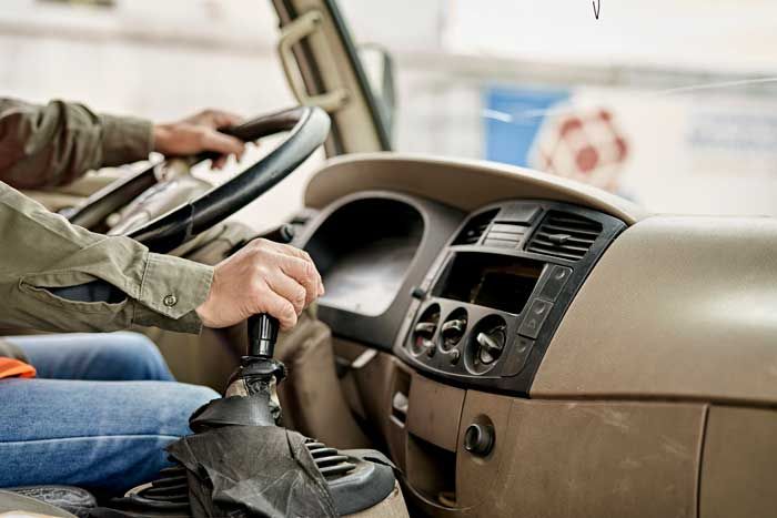 View of a truck driver shifting gears in the cab of his vehicle while driving.