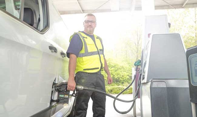 A trucker fueling his rig at a gas station.