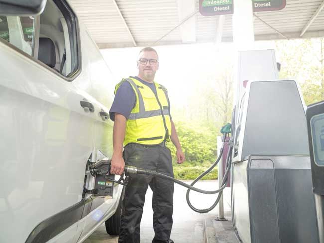 A trucker fueling his rig at a gas station.
